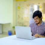 woman in blue and white checkered shirt using macbook